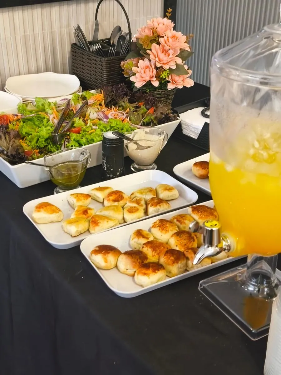 Mesa de buffet com saladas, pães e suco de laranja